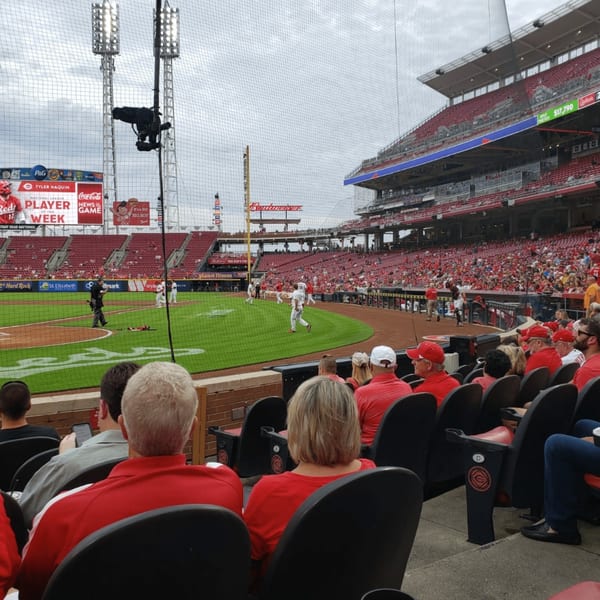 Baseball game in progress at a stadium with many spectators, seen from behind the stands.