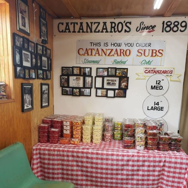 Catanzaro's interior with a red and white checkered table displaying packaged snacks, and historical photos on the wall.