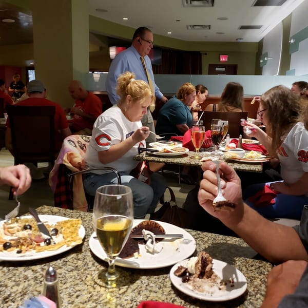 Diners enjoying meals and desserts at tables in a bustling Catanzaro's Pizza & Subs restaurant.