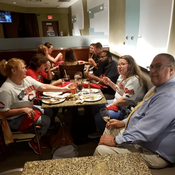 A group of people enjoying a meal and drinks at tables in a restaurant.