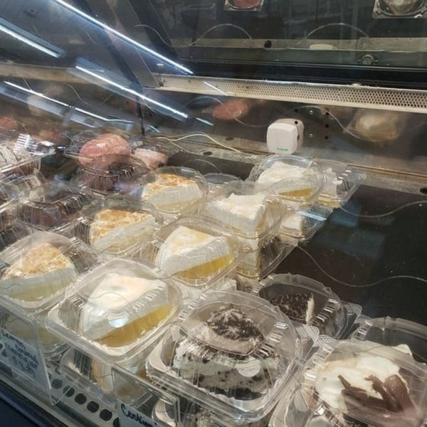 Dessert display case at Catanzaro's Pizza & Subs, featuring various cakes and pies in plastic containers.