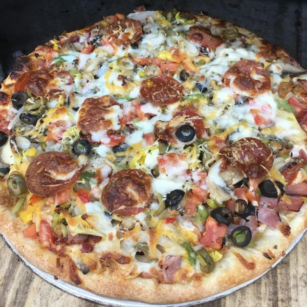 A close-up of a Catanzaro's Pizza & Subs pizza, loaded with pepperoni, olives, and vegetables.